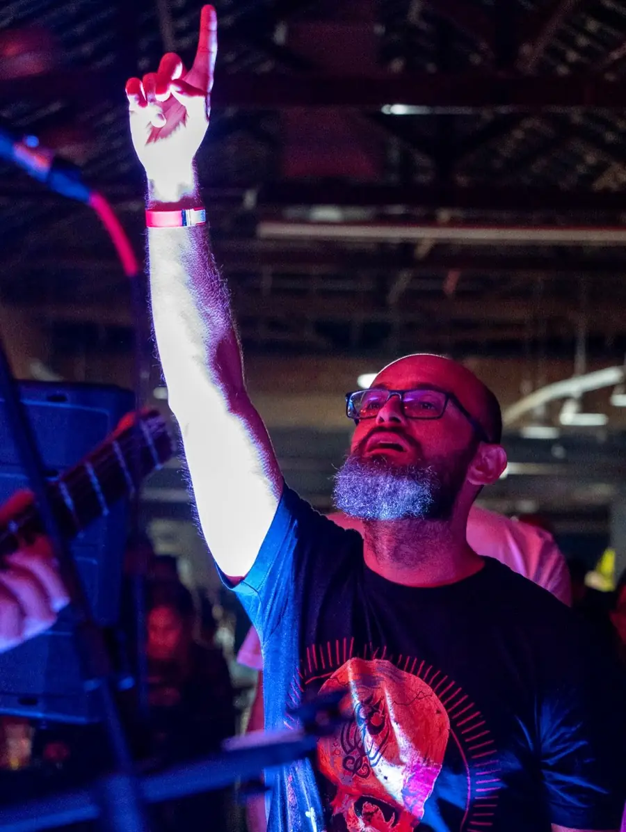 Homem de barba levanta o braço durante um show