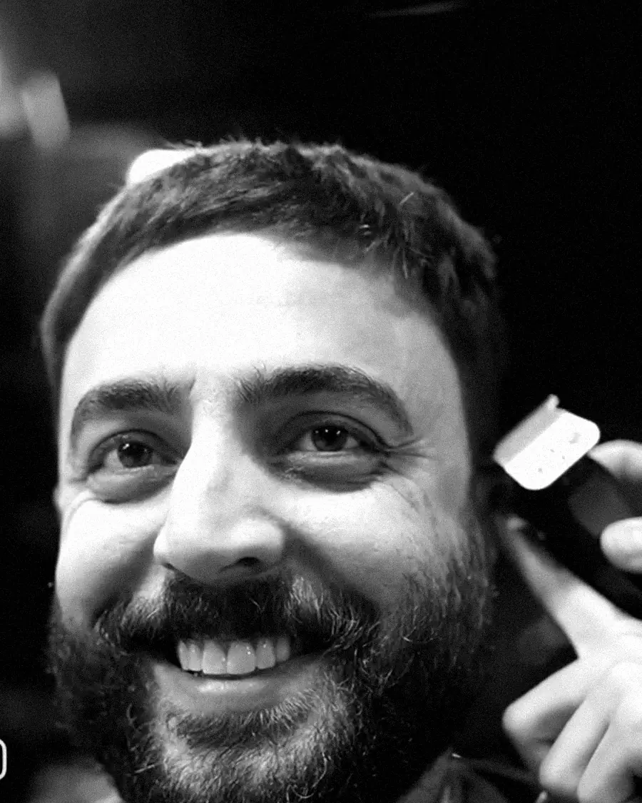 Cliente sorrindo durante o acabamento da barba